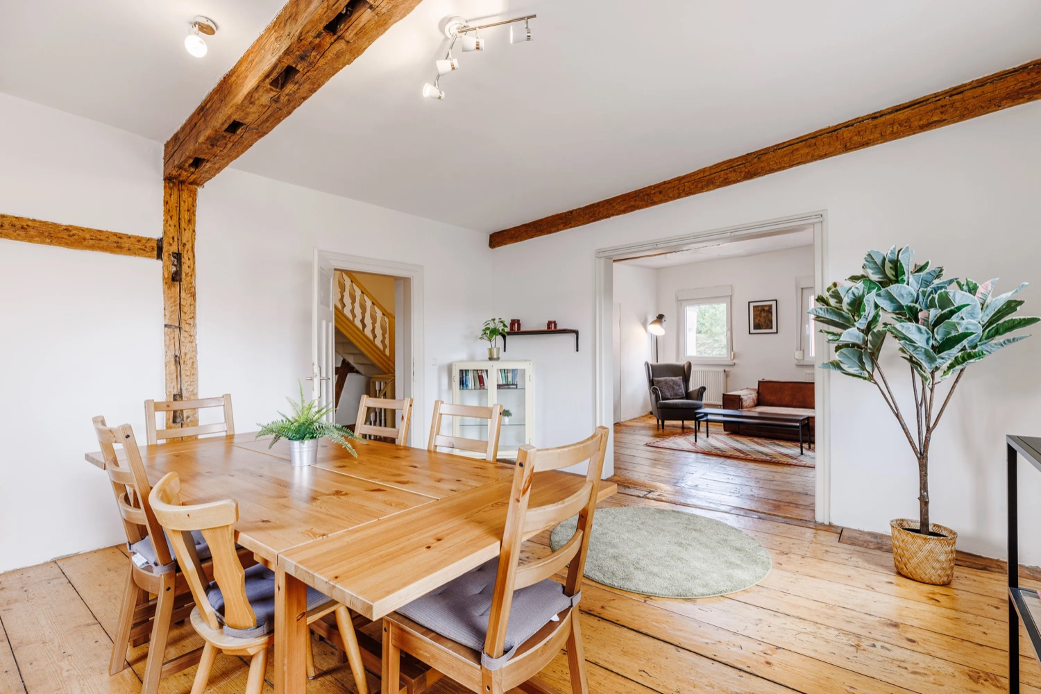 Helles Esszimmer einer Nova-Ferienwohnung mit Holztisch und freigelegten Deckenbalken