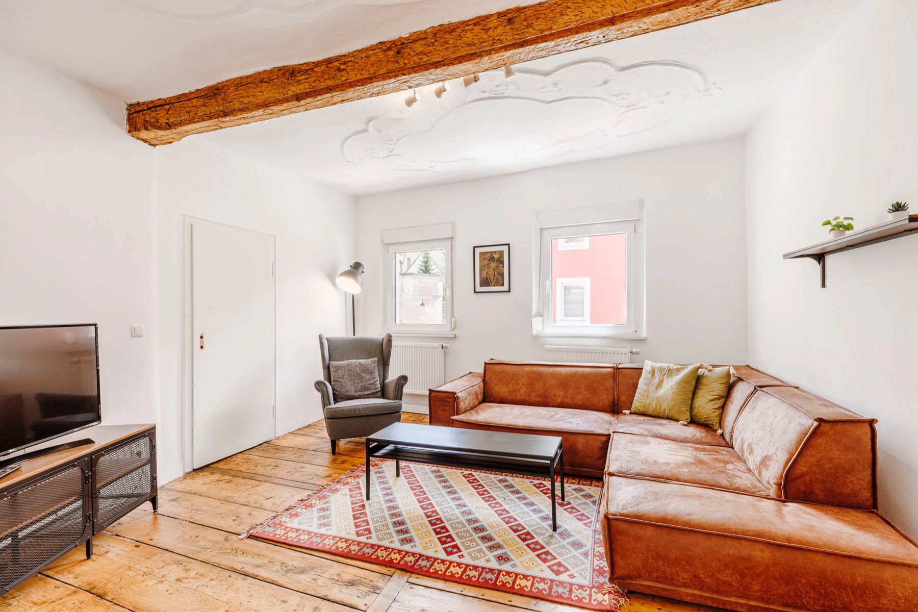 Wohnzimmer einer Nova-Ferienwohnung in Kulmbach mit Ledersofa und freigelegten Holzbalken